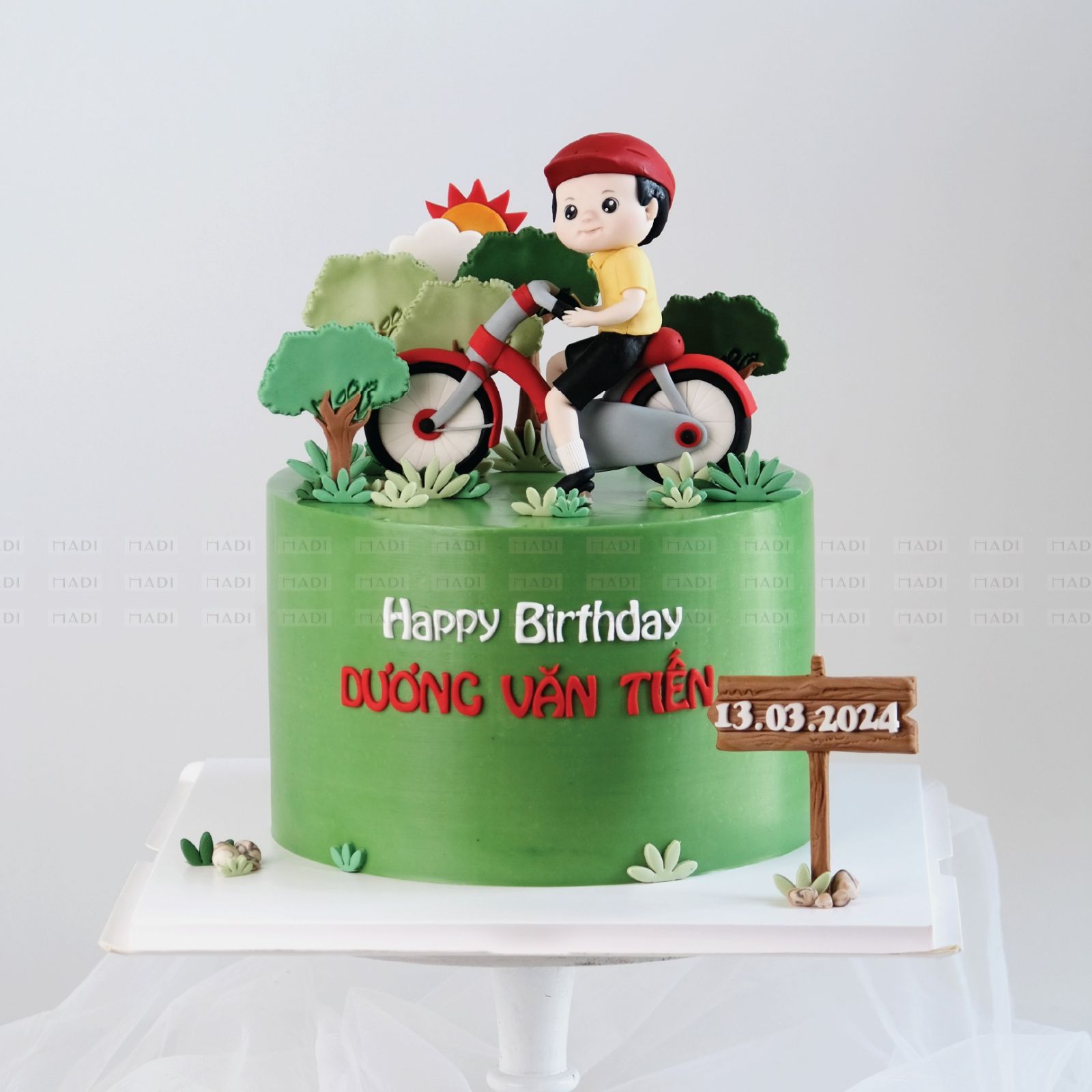 Bánh kem đầy tháng bé lấy cảm hứng từ hình ảnh bé trai trên chiếc xe đạp đỏ nổi bật giữa khung cảnh xanh mát, mang đến cảm giác vui tươi và tràn đầy sức sống