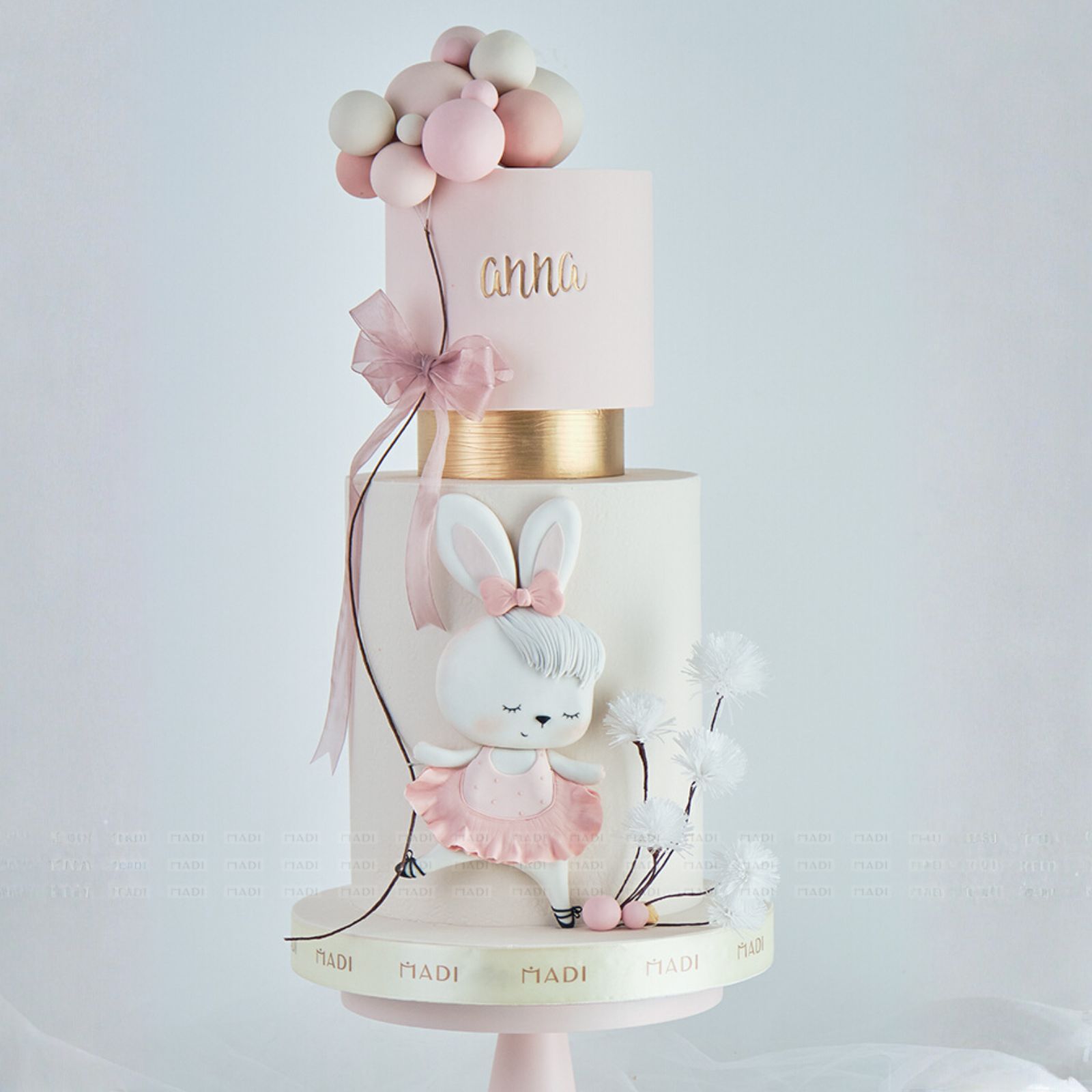 Bánh kem thôi nôi 2 tầng cho bé gái với tạo hình thỏ ngọc đáng yêu và tông hồng pastel xinh xắn, mang đến vẻ ngọt ngào cho ngày vui đầu đời của bé