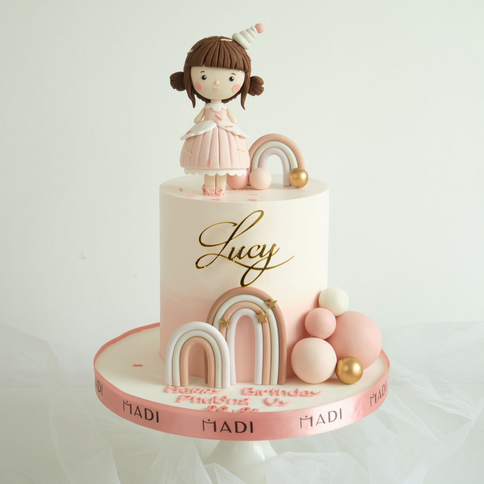 Bánh kem thôi nôi đẹp tạo hình bé Lucy cùng cầu vồng đôi, tượng trưng cho những tháng ngày hạnh phúc, an yên và ngập tràn yêu thương dành cho bé